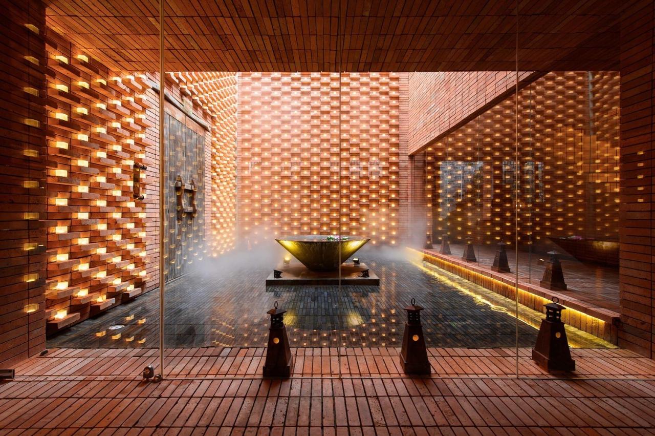 A serene architectural space featuring textured brickwork, a reflective water feature, and strategically placed lighting.