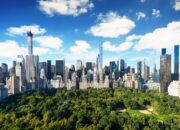 A panoramic view of skyscrapers surrounding a large, dense green park, showcasing urban development alongside nature.