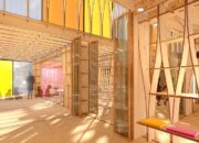 A brightly lit, open-plan interior with wooden structural elements, translucent partitions, and colorful accents, including yellow, orange, and red panels.