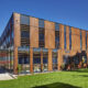 A contemporary office or commercial building with a mix of wood paneling and dark-framed windows.