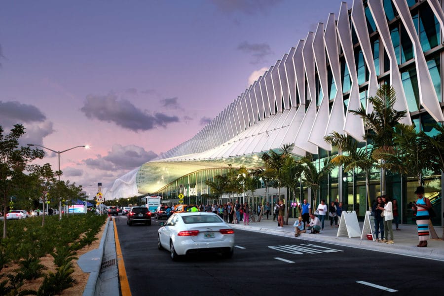 A busy street scene in front of a contemporary architectural structure with palm trees.