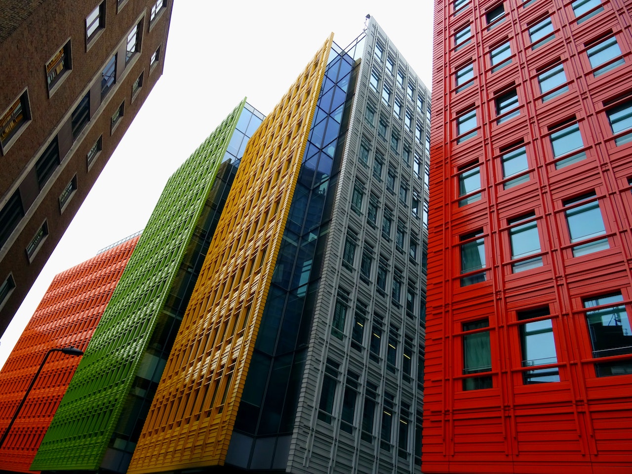Contemporary urban architecture featuring tall structures with geometric patterns and a mix of glass and solid panels.